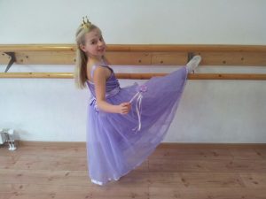 Kindertanz / Kinderballett:  Mädchen im lila Kleid mit einem Fuß auf der Ballettstange