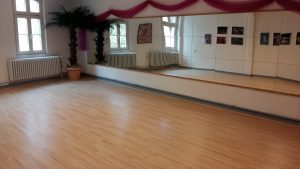 Tanzstudio mit Laminatboden, großem Spiegel und Palmendekoration